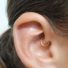 a woman's ear is shown with a single ring on the end of it