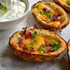 three mini quiches with bacon, green onions and sour cream on the side next to a bowl of sour cream