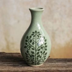 a green vase sitting on top of a wooden table