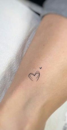 a small heart tattoo on the left inner arm, with an arrow in the middle