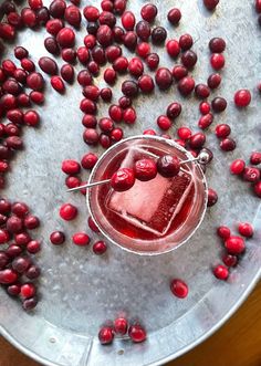 a glass filled with liquid surrounded by pomegranates on top of a table