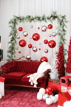 a living room decorated for christmas with red couches and ornaments on the wall behind it