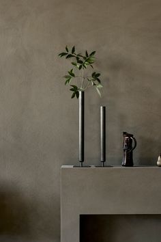 two vases with plants in them sitting on a table next to a wall and chair