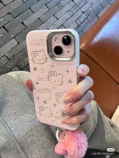 a person holding a hello kitty phone case in their hand with a pink pom - pom