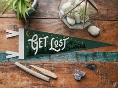 a wooden sign that says get lost on it next to some plants and other items