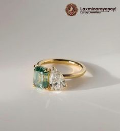 an engagement ring with two pear shaped diamonds and a green tourmaline in the center