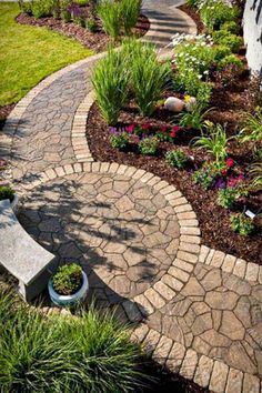 a stone walkway with flowers and plants in the center, along with a bench on the other side