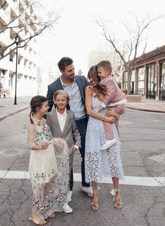 a group of people standing on the side of a road with one woman holding a child