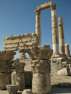 some very old stone pillars in the middle of a dirt field with blue sky behind them