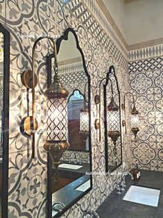 an ornately decorated bathroom with mirrors and lights on the wall, along with a sink