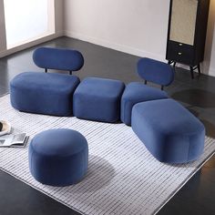 a blue couch sitting on top of a rug next to a chair and footstool