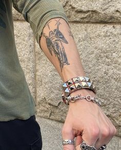 a man with tattoos on his arm holding onto another person's hand and wearing bracelets