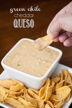 a person dipping tortilla chips into a white bowl