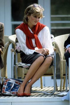 a woman sitting in a chair wearing a red scarf