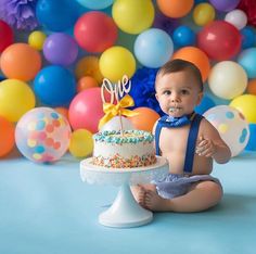 a baby sitting in front of a birthday cake