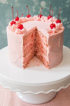 a cake with pink frosting and cherries on top