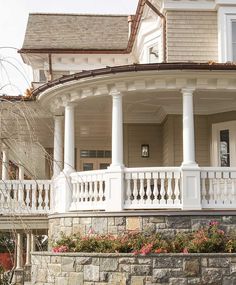 the front porch of a house with white columns and flowers on the planter boxes