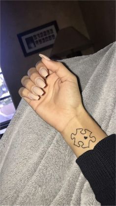 a woman's arm with a tattoo on it that has a puzzle piece in the middle