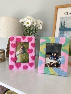 three different colored frames sitting on top of a white table next to a vase with flowers