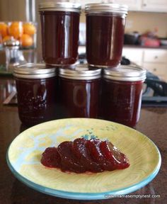 jam on a plate next to several jars of jam in a kitchen setting with oranges behind it