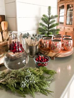 the kitchen counter is covered with silver dishes and greenery, including cranberries