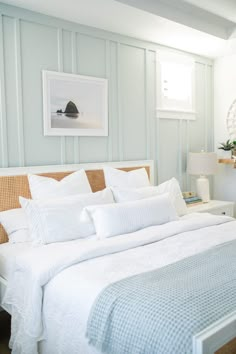 a bed with white sheets and pillows in a bedroom