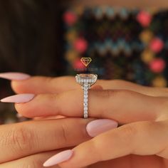 a woman's hand holding an engagement ring with a diamond on the top and side