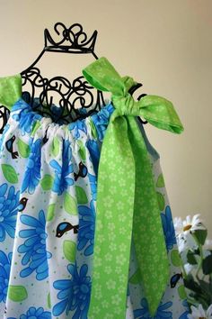 a dress with green and blue flowers on the bottom, tied to a hanger