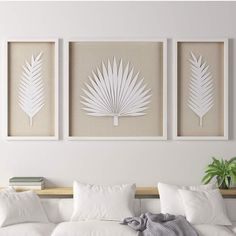 three white palm leaves are hanging on the wall above a couch in a living room