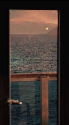 the view from inside a window looking out at the ocean and mountains in the distance