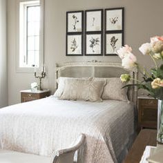 a bed room with a neatly made bed and pictures hanging on the wall above it