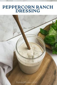 a glass jar filled with dressing sitting on top of a cutting board next to lettuce