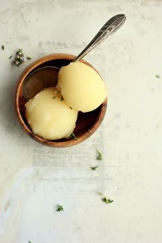 two scoops of ice cream sit in a wooden bowl on a white countertop