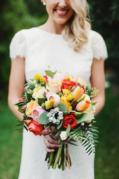 the bride and groom are holding bouquets of flowers in their hands while standing outside