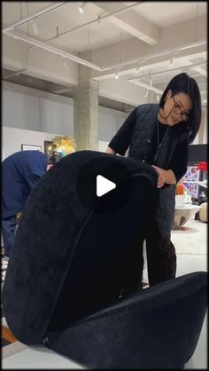 a woman standing next to a large black object