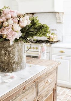 a large metal bucket filled with flowers on top of a wooden table in a kitchen