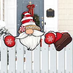 a white picket fence with christmas decorations on it and a santa clause holding candy canes