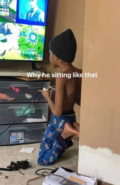 a young boy sitting on the floor in front of a tv