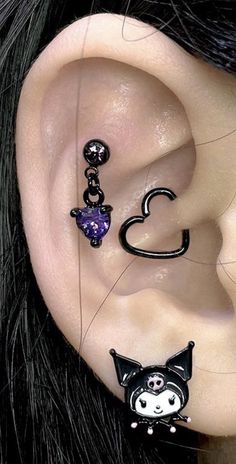 an ear with three different piercings attached to it's sides, one is black and the other is purple