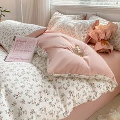 a bed with pink sheets and pillows in front of a window