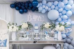 a table topped with lots of blue and white balloons