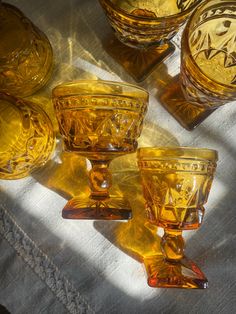 some yellow glass cups and bowls on a white table cloth with sunlight coming through the window