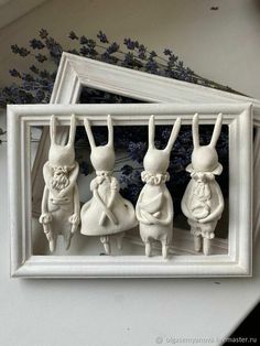 three white rabbits are hanging from a frame