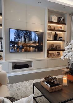 a living room filled with furniture and a flat screen tv mounted on a wall above a fireplace