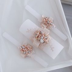 two hair clips with pearls and bows on top of a white sheeted tablecloth