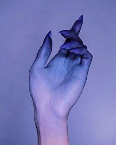 a person's hand holding something up in the air with blue paint on it