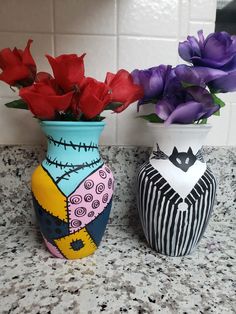 two vases with flowers in them sitting on a counter top next to each other