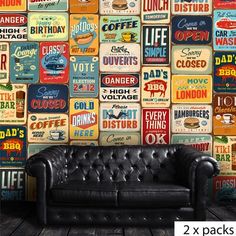 a black leather couch sitting in front of a wall covered with colorful signs and advertisements