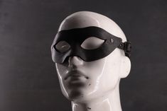 Dare to embrace your dark side with our sleek, winged leather mask. This black-on-black look adds a sense of bold mystery, perfect for those who command attention without saying a word. Sabersmyth's leather masks are a bold blend of artistry, comfort, and durability. Each mask is expertly shaped to fit the unique contours of your face, offering both a snug fit and lasting comfort. Spacious eye openings ensure clear peripheral vision and won't interfere with your makeup, while our signature head cradle design guarantees a secure, comfortable wear. Designed to make a statement and built to last, these masks will be the envy of every event. Leather Masks, Embrace Your Dark Side, Peripheral Vision, Costume Masks, Mask Black, Leather Mask, Costume Mask, Black Hardware, Costume Accessories