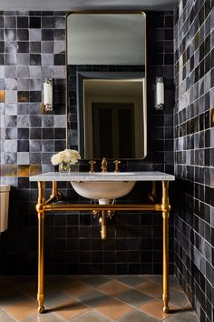 a white sink sitting under a bathroom mirror next to a gold faucet mounted on a wall